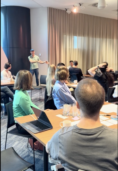 A standing participant speaking while others listen from their tables.