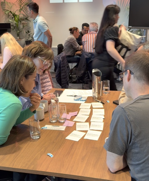 Participants leaning over printed discussion cards arranged on a table.